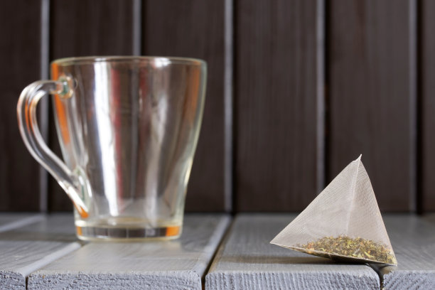金字塔茶包与绿茶躺在复古的桌子上，由天然木板制成的透明杯子旁边。卡车司机自助路边咖啡馆的元素。生态斯堪的纳维亚风格图片下载
