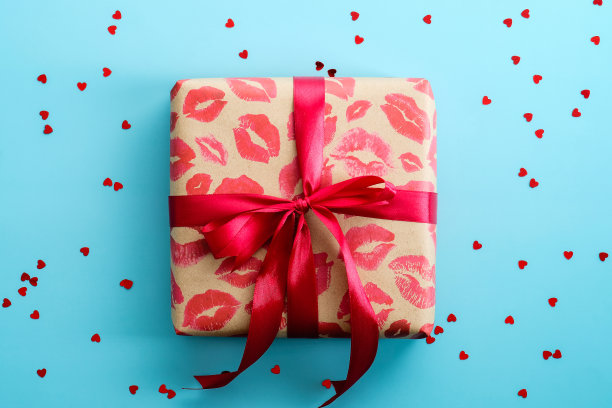 红丝带系的礼盒，蓝色的背景上撒着五彩纸屑。情人节快乐的概念。图片下载