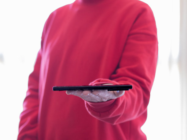 穿红毛衣的女孩抱着智能手机商务互联网技术的概念图片下载