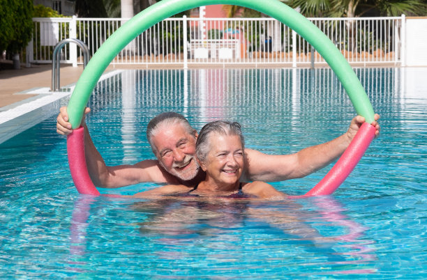 快乐的成年人快乐的老夫妇在户外游泳池做游泳面乐趣。微笑的退休人员在阳光下一起在泳池里玩耍图片下载