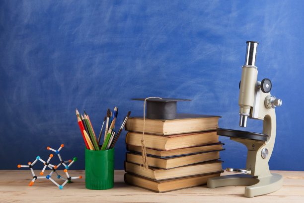 教育和科学概念——课本放在礼堂的老师桌上，黑板放在背景上。图片下载