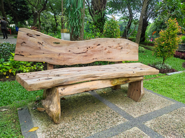 艺术和手工家具产品的花园椅，由大型旧原木在公园的自然背景。图片下载