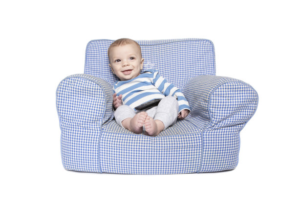 快乐的小男孩坐在椅子上，腿上放着遥控器图片下载