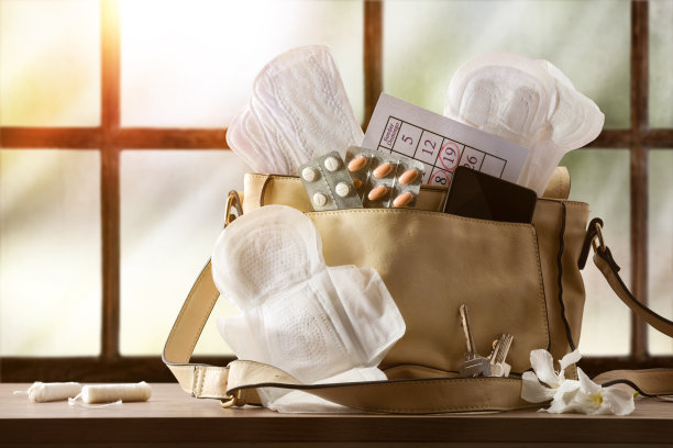 家用窗户背景的桌子上放有月经用品的钱包图片下载