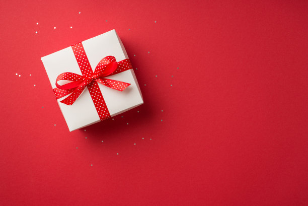俯视图照片的情人节装饰发光的亮片白色礼品盒与红色圆点丝带蝴蝶结孤立的红色背景与空白空间图片下载