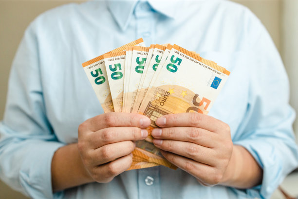 钱的赢家。女商人手里拿着灰色背景的欧元图片下载