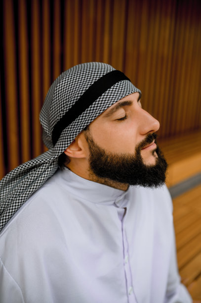 闭着眼睛平静坐着的年轻阿拉伯男子图片下载