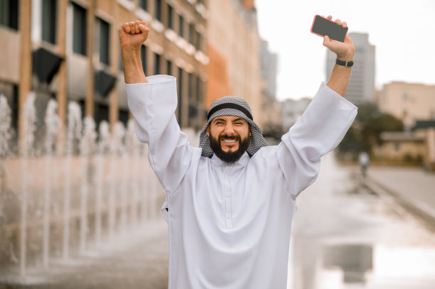 拿着手机看起来很兴奋的中东青年男子图片下载