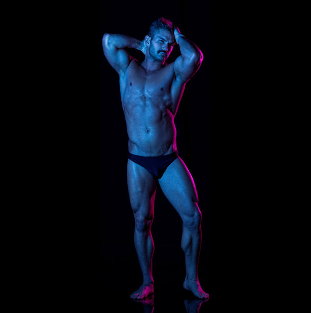 白人男性穿着赛车内裤站在黑色背景前图片下载