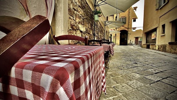 在意大利托斯卡纳的佛罗伦萨，户外餐桌排成一排，沿着一条狭窄的石头走道逐渐缩小。图片下载