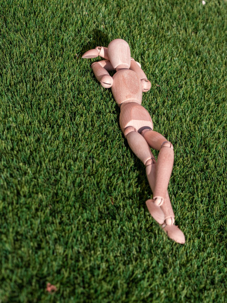 木制娃娃躺在草地上放松地晒日光浴图片下载