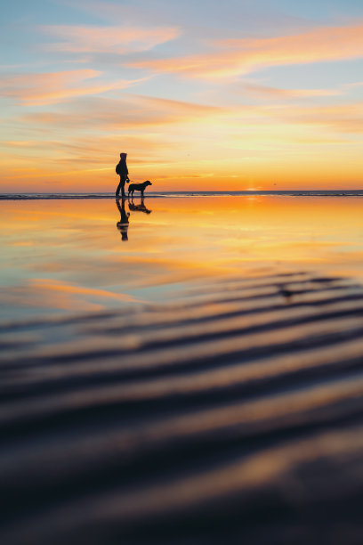 落日余晖映照在湖面或海面上的男人的剪影。夕阳下的女人或男人图片下载