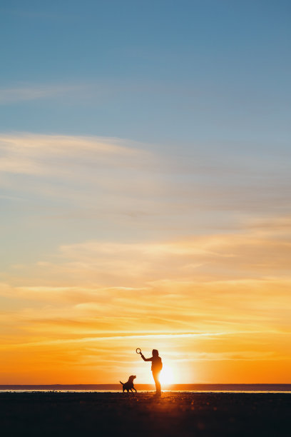 落日余晖映照在湖面或海面上的男人的剪影。夕阳下的女人或男人图片下载