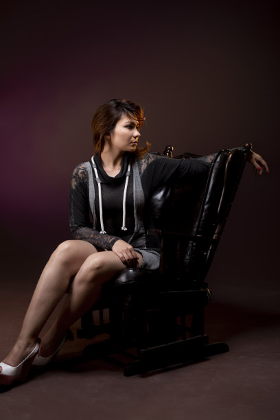女人坐在椅子上看着相机，背景是黑色和纹理。图片下载