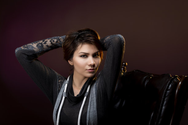 女人坐在椅子上看着相机，背景是黑色和纹理。图片下载