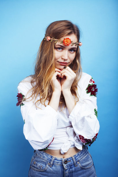 年轻漂亮的金发女孩摆姿势在蓝色的背景，时尚风格的嬉皮波西米亚花头上图片下载