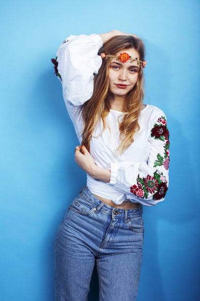 年轻漂亮的金发女孩摆姿势在蓝色的背景，时尚风格的嬉皮波西米亚花头上图片下载