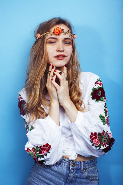 年轻漂亮的金发女孩摆姿势在蓝色的背景，时尚风格的嬉皮波西米亚花头上图片下载