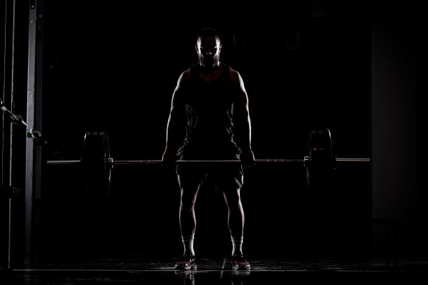 运动员举起杠铃。一个肌肉发达男人的剪影图片下载