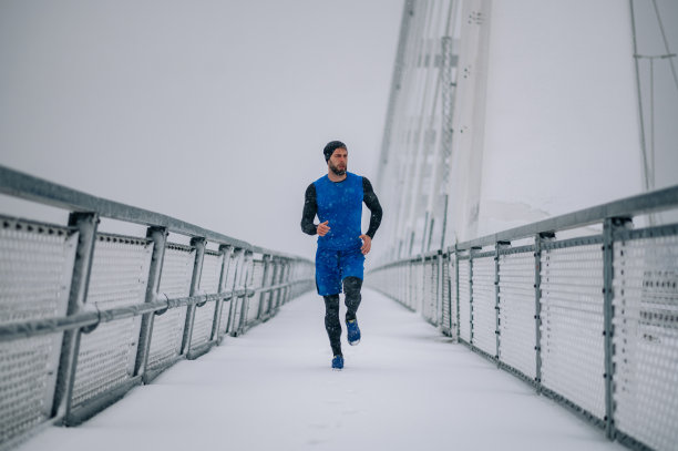 帅气的白种人穿着运动服在雪桥上奔跑。健康的运动员在寒冷的冬天跑步。城市城市慢跑者。图片下载