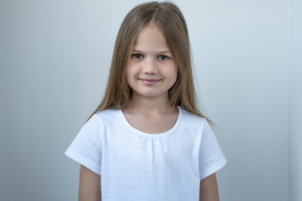可爱的小白种人学校女孩的肖像在白色t-short灰色的背景微笑。可爱的孩子看着镜头图片下载