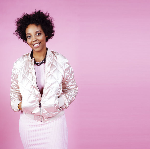 年轻漂亮时尚风格的非洲女孩摆出情绪愉悦的粉红色背景，生活方式的人的概念图片下载