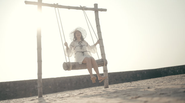 一个快乐的女人在海边的沙滩上荡秋千图片下载