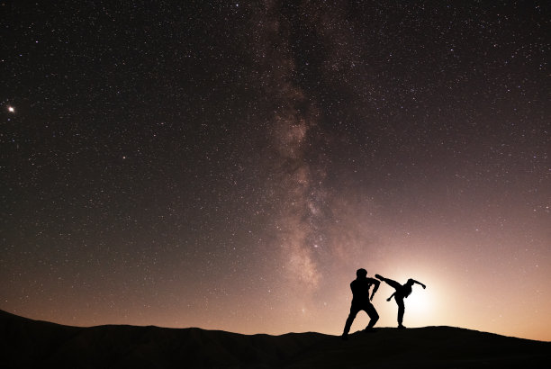 星空背景下空手道选手的剪影。美丽的银河系。晚上scenne。图片下载