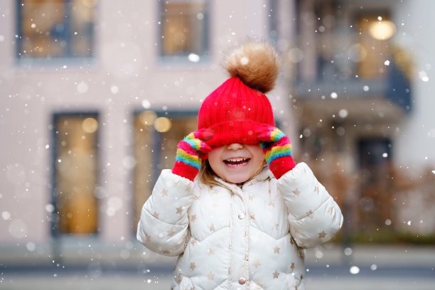 穿着冬装的学前班小女孩的滑稽画像。快乐积极的孩子戴着红帽子和五颜六色的手套在户外。冬天的一天。图片下载