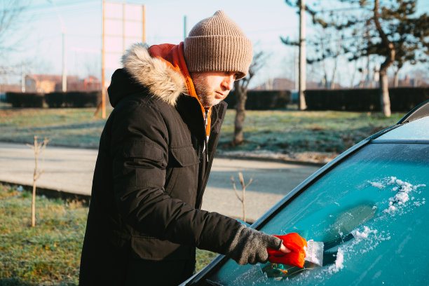 冬天的早晨，一名男子从车上刮冰图片下载
