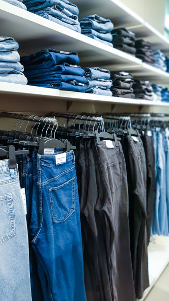 不同颜色、质地和色调的牛仔裤整齐地堆放在品牌时装店的橱窗柜台上图片下载
