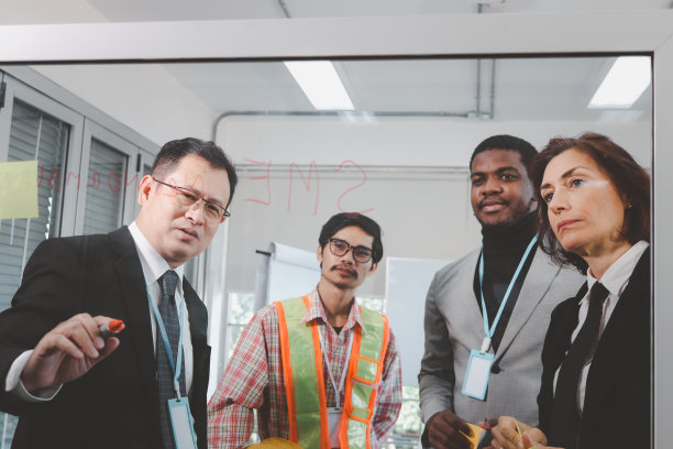 资深亚洲商人西装笔头在玻璃板上书写，在办公室进行创意头脑风暴，在项目工作中进行批判性思考，公司同事讨论结果，多元种族的团队同事一起工作图片下载