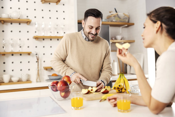 在他们舒适的公寓里，一个男人在厨房里为他的妻子准备健康的零食。图片下载