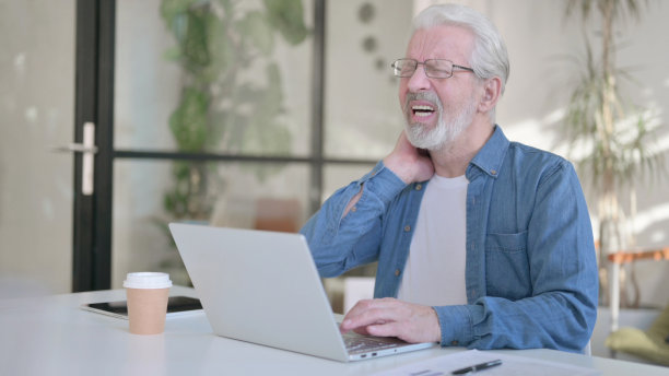 老人在办公室使用笔记本电脑时脖子痛图片下载