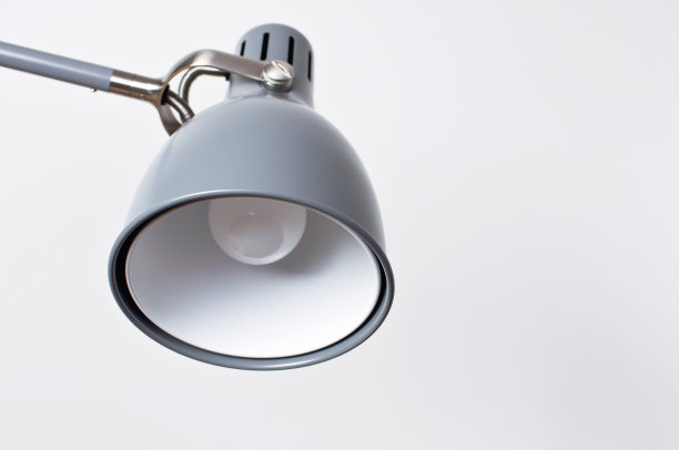 室内一盏灰色的台灯靠在白色的墙上。商业或教育的概念，为你的文本提供一个地方。室内细节，极简主义背景。图片下载