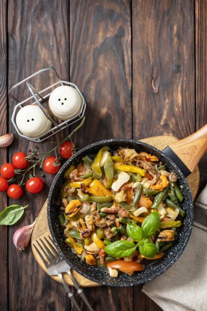 海鲜烩肉，健康的地中海晚餐。海鲜虾，鱿鱼，墨鱼，蔬菜和大蒜酱在煎锅里炖，放在木桌上。俯视图平躺。副本的空间。图片下载