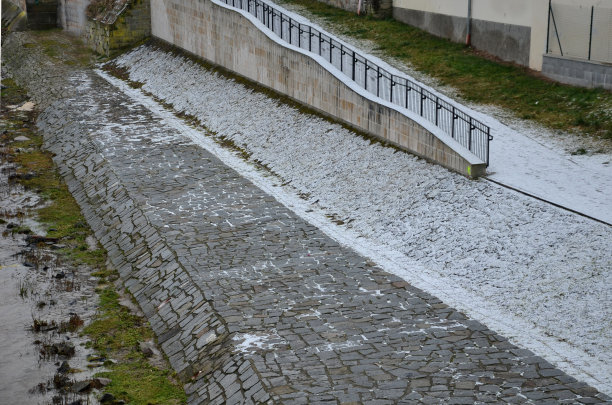 水边有一个为骑自行车和滑冰的人准备的坡道，上面覆盖着积雪。波涛汹涌，河水浑浊。河上的金属黑色栏杆图片下载