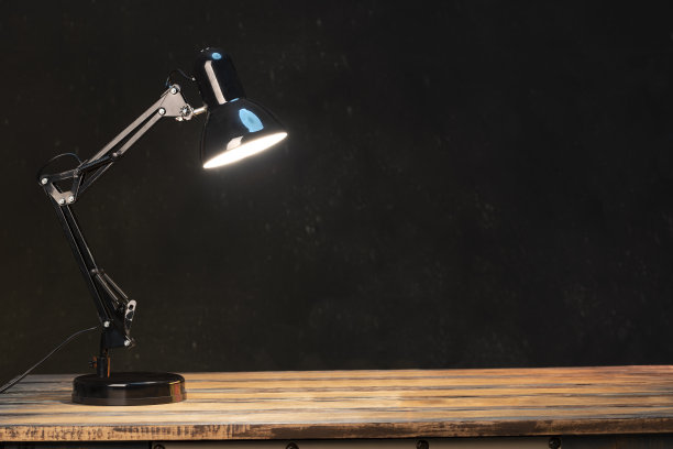 在黑色背景的木制桌面上的黑色灯的近距离视图。图片下载