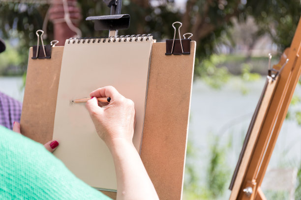 女人用木炭在河岸上作画图片下载