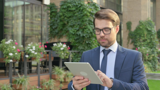 年轻的商人走在街上用平板电脑图片下载