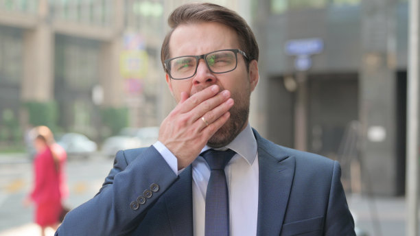 年轻的商人站在户外打哈欠图片下载