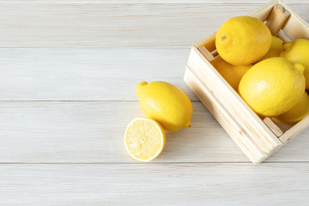 木盒里的熟柠檬。白色木质背景上的新鲜柠檬。成熟可口的柑橘类水果。图片下载