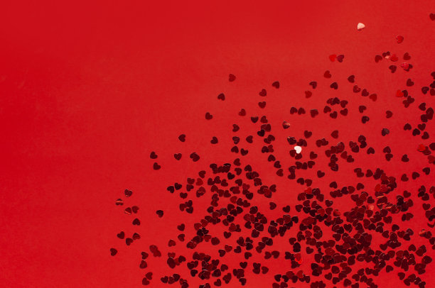 平铺红色纸屑在形状的心脏在红色背景顶视图。节日背景，情人节，派对概念，爱情，生日，圣诞节或新年。Copyspace文本图片下载