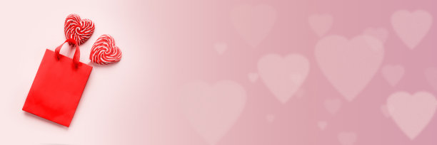 红色购物袋与两个心形棒棒糖在粉红色的情人节背景横幅大小图片下载