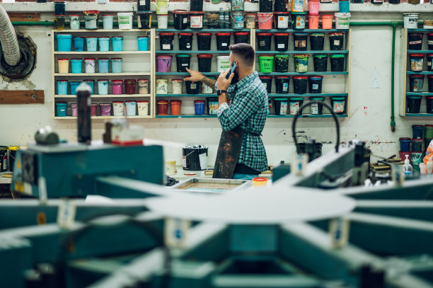 男工人在车间里用智能手机为丝网印刷调色图片下载