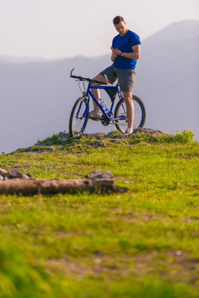 适合山地自行车骑他的自行车通过绿色的草地在山顶的一个山。图片下载