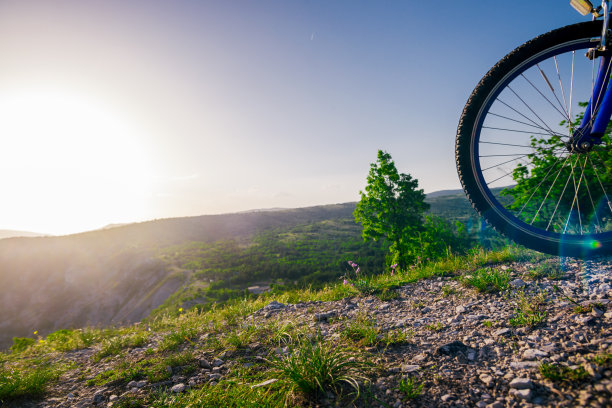 近距离的照片，一个山地车骑他的自行车(自行车)在崎岖的岩石山顶上，没有穿安全设备。肾上腺素迷。图片下载