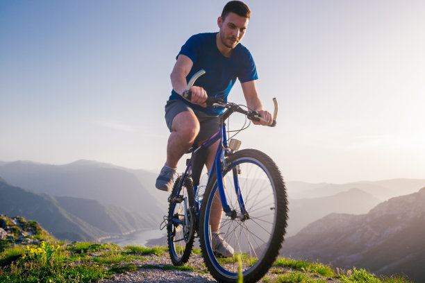 近距离的照片，一个山地车骑他的自行车(自行车)在崎岖的岩石山顶上，没有穿安全设备。肾上腺素迷。图片下载