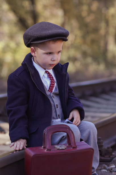 复古照片，一个孩子提着行李箱在枕边行走图片下载