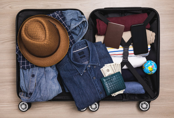 俯视图组织行李。把衣服和裤子放在手推车里，准备出国。为暑假旅行准备行李。旅行者配件，打开行李。图片下载